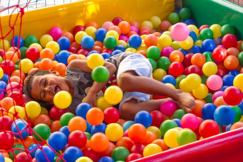 A laughing child playing in a ball pit full of colourful balls